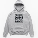 Typography reading TRUST ME I'M ALMOST DONE MAYBE with a 73 percent loading bar graphic on a Hoodie.